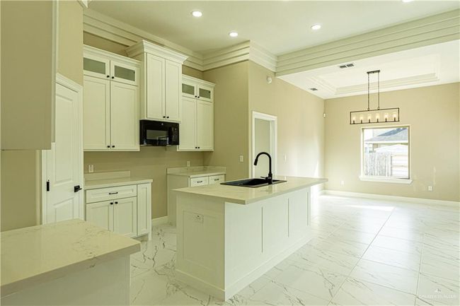 Kitchen featuring marble finish floor, a center island with sink, a sink, black microwave, and baseboards | Image 32