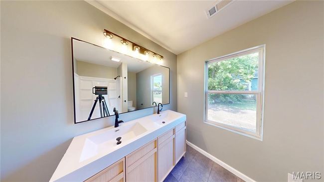 Full bath featuring toilet, baseboards, double vanity, tile patterned flooring, and a shower | Image 15