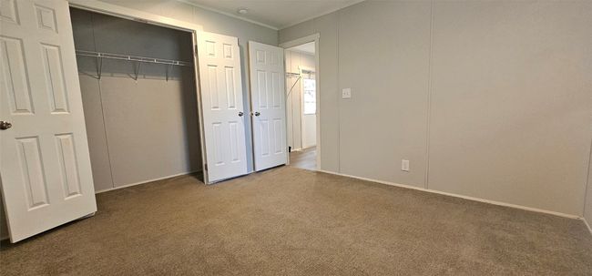 Unfurnished bedroom with carpet floors, a closet, and crown molding | Image 11