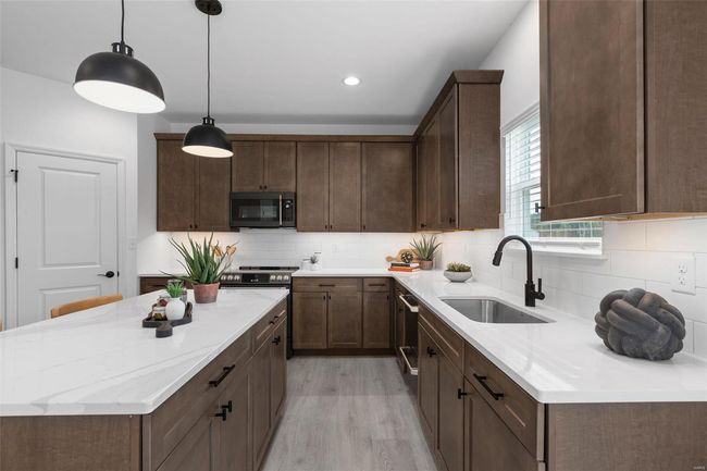 Kitchen with pendant lighting, light wood-type flooring, dark brown cabinets, sink, and backsplash | Image 12