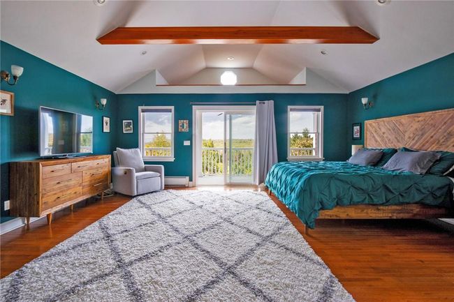 Bedroom with access to outside, vaulted ceiling with beams, dark hardwood / wood-style floors, and a baseboard heating unit | Image 19
