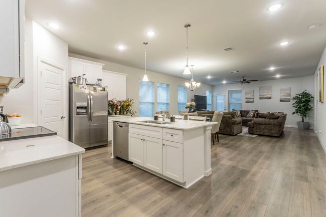 Kitchen with stainless steel appliances, a sink, a chandelier, light wood-type flooring, and white cabinets | Image 6