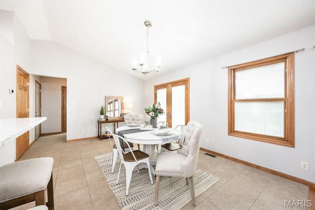 Dining space with a chandelier, lofted ceiling, light tile patterned flooring, and baseboards | Image 15