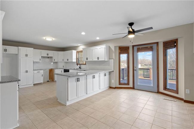 Kitchen with a peninsula, a wealth of natural light, light stone countertops, and a sink | Image 28