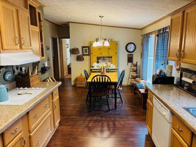 Kitchen featuring dark wood-style flooring, ornamental molding, a chandelier, white appliances, and exhaust hood | Image 17