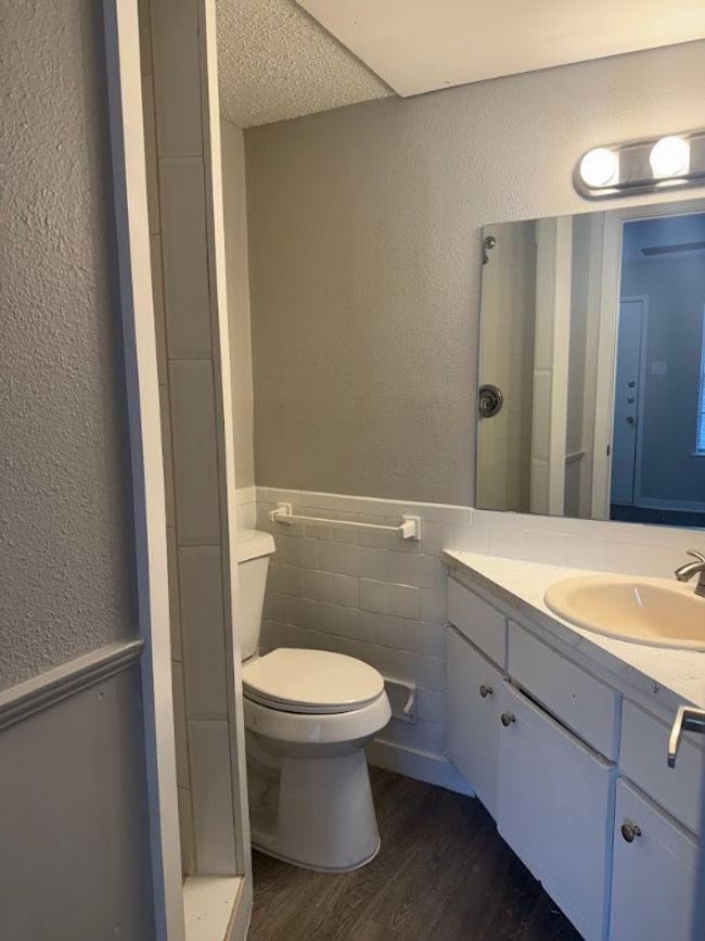 Full bathroom with wood finished floors, toilet, wainscoting, vanity, and tile walls | Image 22