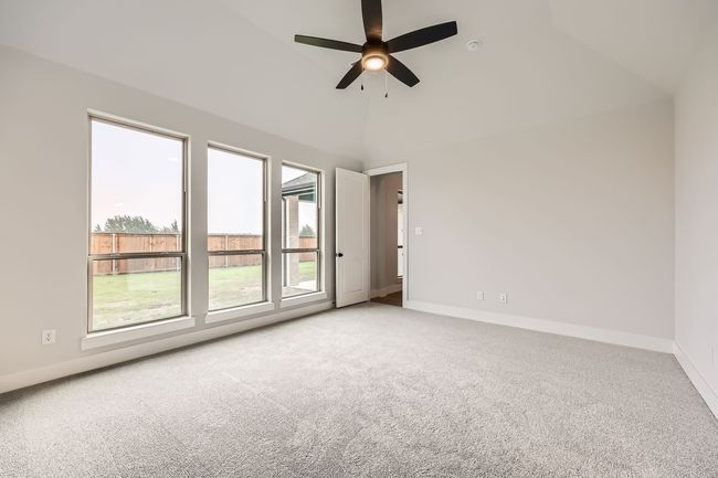 Spare room featuring baseboards, ceiling fan, vaulted ceiling, and light colored carpet | Image 14