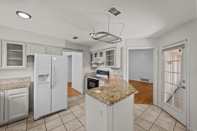 Kitchen featuring range with electric cooktop, white fridge with ice dispenser, under cabinet range hood, a peninsula, and glass insert cabinets | Image 17