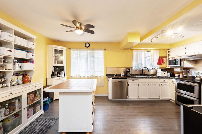 Kitchen featuring appliances with stainless steel finishes, dark wood-style flooring, white cabinetry, and a ceiling fan | Image 11
