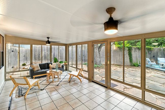 Sun-filled, air-conditioned sunroom provides flexible space for a second living area, home office, gym, or entertainment zone. With tile flooring and expansive backyard views, it’s a perfect bridge between indoor comfort and outdoor charm. | Image 20