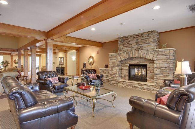 A favorite gathering spot featuring a cozy stone fireplace, rich woodwork, beamed ceilings, and plush leather seating that invites relaxation and connection. | Image 22