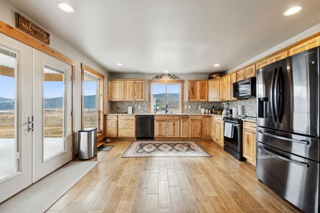 Kitchen with black appliances, light wood-type flooring, a mountain view, sink, and backsplash | Image 29