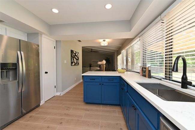 Kitchen with stainless steel fridge, blue cabinets, wood tiled floors, a peninsula, and recessed lighting | Image 10