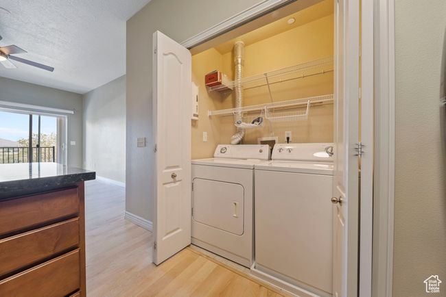 Washroom featuring independent washer and dryer, light wood-type flooring, baseboards, ceiling fan, and a textured ceiling | Image 5