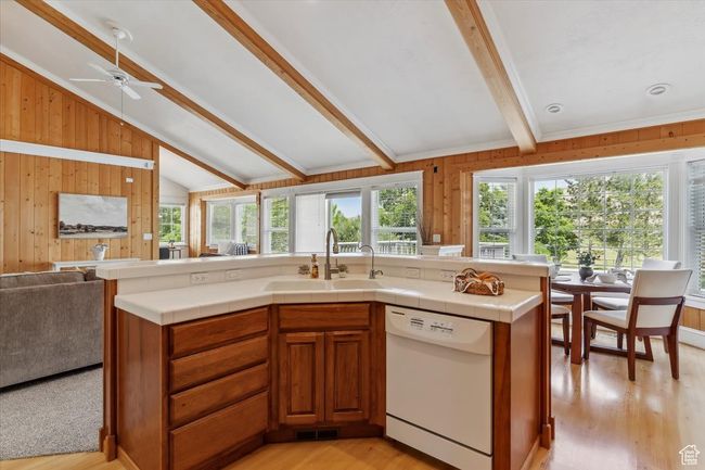Kitchen featuring white dishwasher, a sink, open floor plan, plenty of natural light, and wooden walls | Image 12