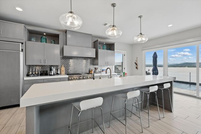 Kitchen featuring built in refrigerator, gray cabinetry, decorative backsplash, and open shelves | Image 19