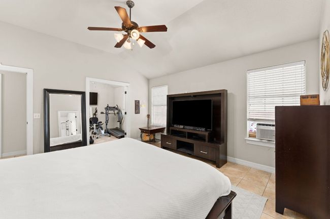 Bedroom with vaulted ceiling, light tile patterned floors, a ceiling fan, and baseboards | Image 13