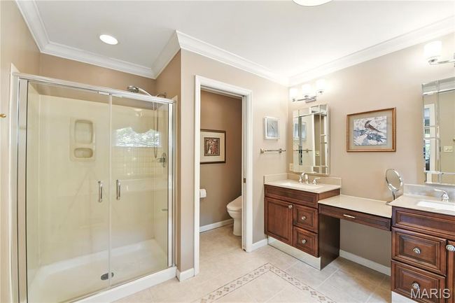 Bathroom with a shower stall, tile patterned floors, ornamental molding, and two vanities | Image 12