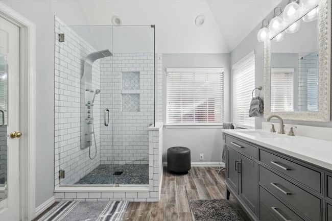 Bathroom featuring wood finished floors, a stall shower, vaulted ceiling, vanity, and baseboards | Image 17
