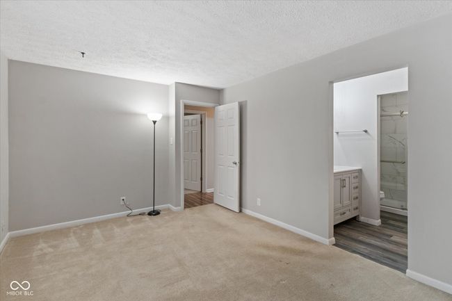 unfurnished bedroom with carpet floors, a textured ceiling, and ensuite bathroom | Image 13