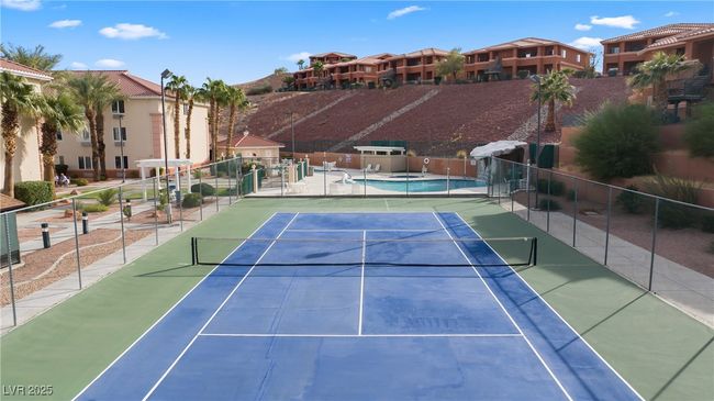 View of tennis court with fence and a residential view | Image 47