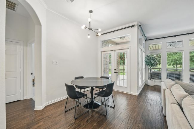 Dining space featuring crown molding, french doors, arched walkways, dark wood-style flooring, and a chandelier | Image 12