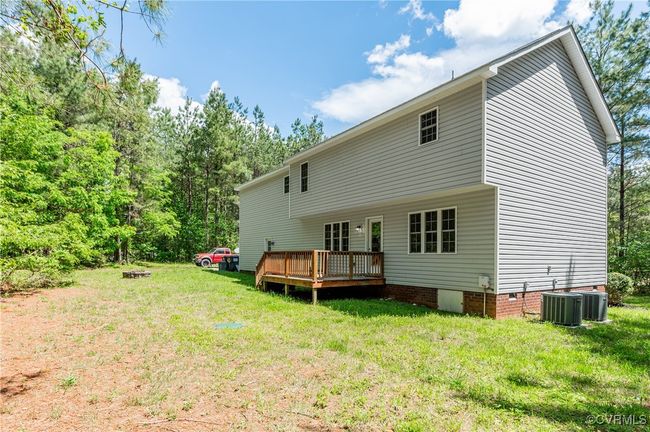 Rear view of house featuring a wooden deck, a yard, crawl space, and central air condition unit | Image 30