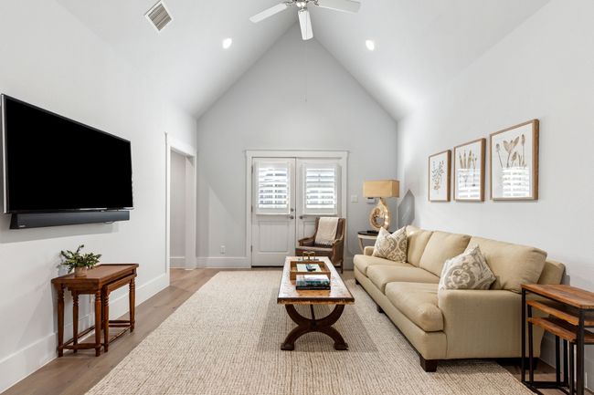 Living room with high vaulted ceiling, wood finished floors, baseboards, visible vents, and ceiling fan | Image 24
