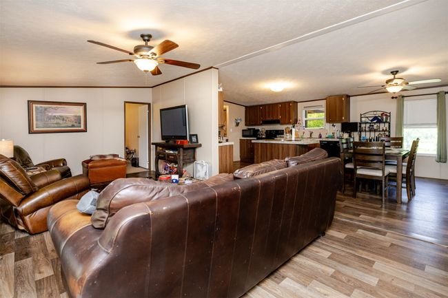 Living room with ornamental molding, a ceiling fan, and light wood finished floors | Image 4