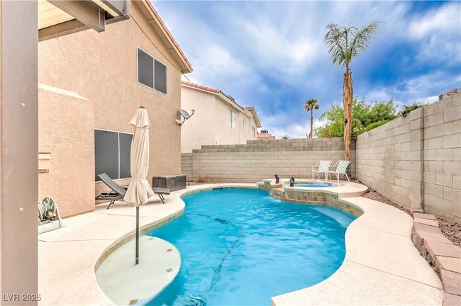 View of swimming pool with a fenced backyard, a pool with connected hot tub, and a patio area | Image 37