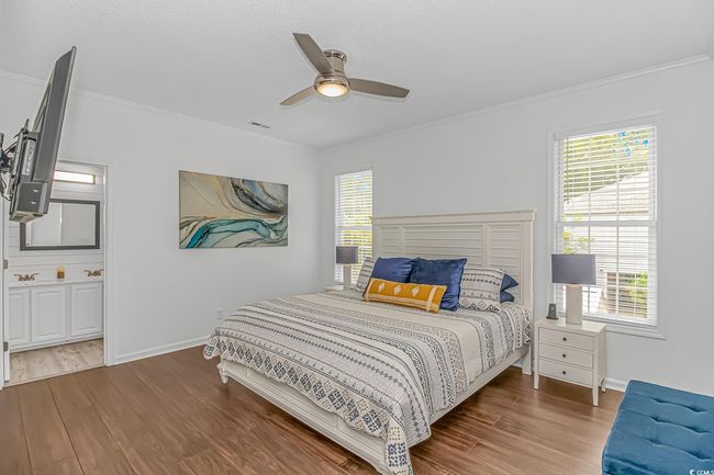 Bedroom with wood finished floors, crown molding, multiple windows, baseboards, and connected bathroom | Image 15
