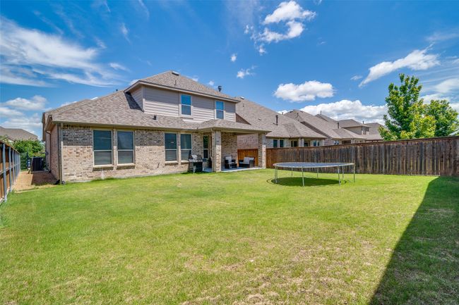 Back of house with a fenced backyard, brick siding, roof with shingles, a patio, and a trampoline | Image 28