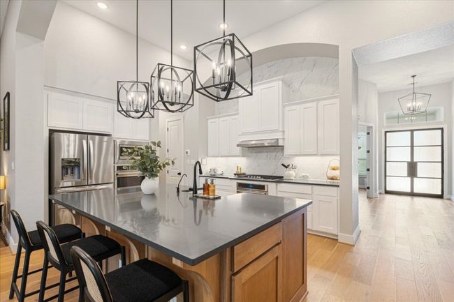 Kitchen with a chandelier, a sink, dark countertops, stainless steel appliances, and light wood-style flooring | Image 14