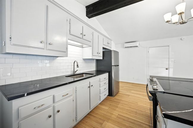 Kitchen featuring electric range, a wall mounted AC, dark countertops, freestanding refrigerator, and backsplash | Image 12