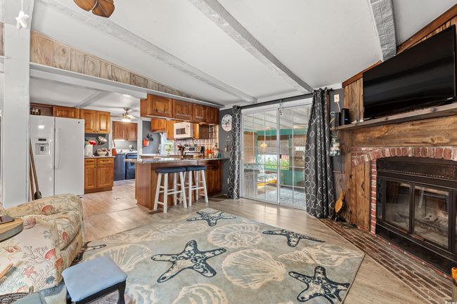 Living room with lofted ceiling with beams, light hardwood / wood-style floors, a fireplace, and ceiling fan | Image 5