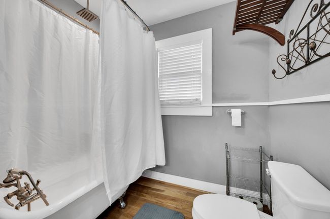 Full bath featuring toilet, wood finished floors, baseboards, and shower / bath combo with shower curtain | Image 13
