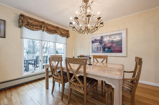 Dining area featuring baseboards, wood finished floors, ornamental molding, and an inviting chandelier | Image 11