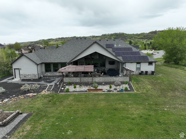 Rear view of property with a deck, a yard, a shingled roof, solar panels, and a vegetable garden | Image 56