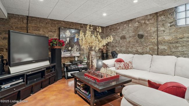 Lower level living room with exposed stone walls. | Image 38