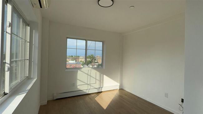 Unfurnished room with a baseboard heating unit and wood finished floors | Image 11