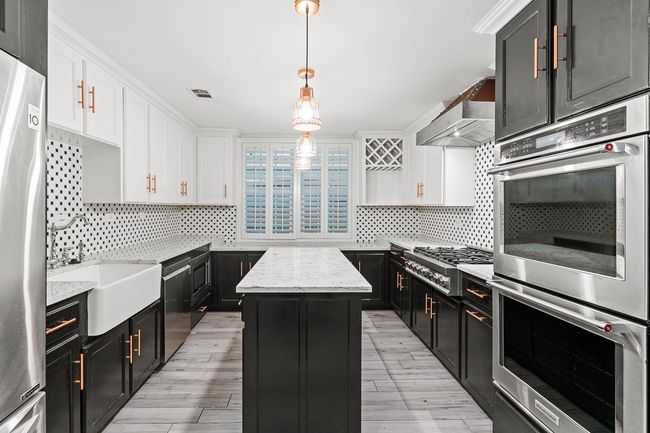 Kitchen featuring stainless steel appliances, dark cabinetry, white cabinets, and a kitchen island | Image 19