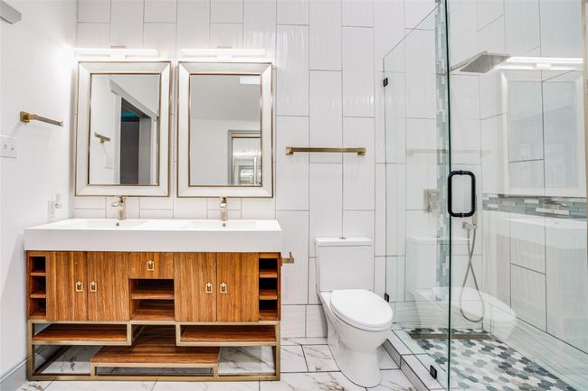 Full bathroom with a stall shower, double vanity, toilet, and marble finish floors | Image 20