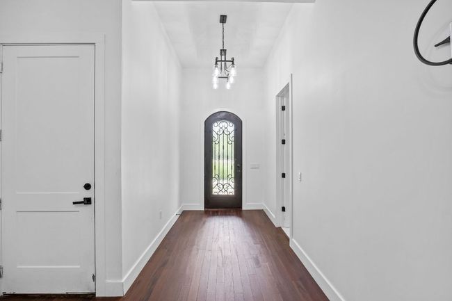 Entryway with a chandelier, dark wood-style flooring, and arched walkways | Image 4