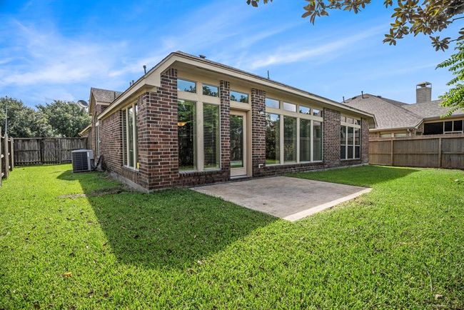 A wall of windows overlooks the fully fenced backyard, giving you great natural light indoors and views outside. The open patio area offers space for seating or a grill, and the yard is easy to care for with just the right amount of green space. | Image 30