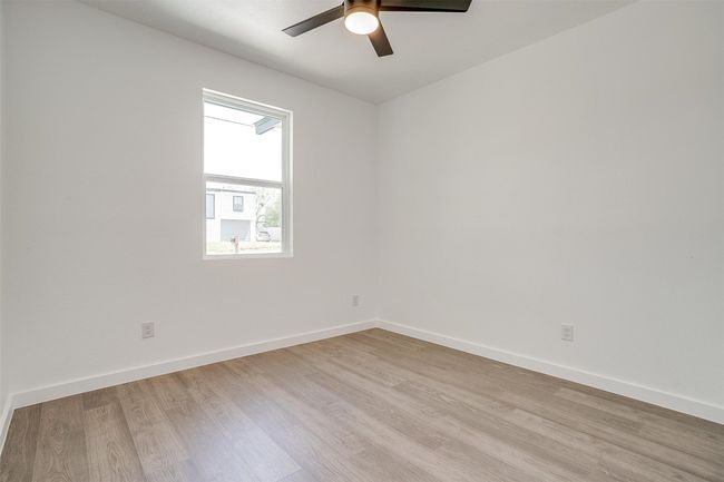 Empty room with light wood-style floors, baseboards, and a ceiling fan | Image 31