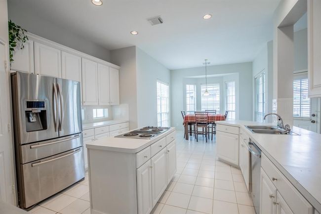 Bright, spacious kitchen with white cabinetry, and a central island. The large breakfast area features large windows, offering plenty of natural light. | Image 24