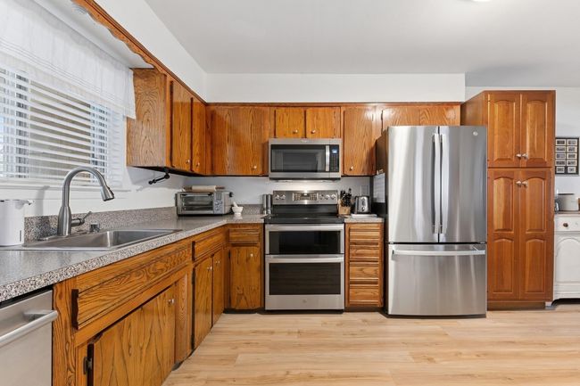 Kitchen with a sink, brown cabinetry, appliances with stainless steel finishes, and light wood finished floors | Image 8