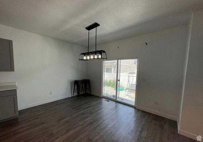 Unfurnished dining area with dark wood-style flooring and a chandelier | Image 8