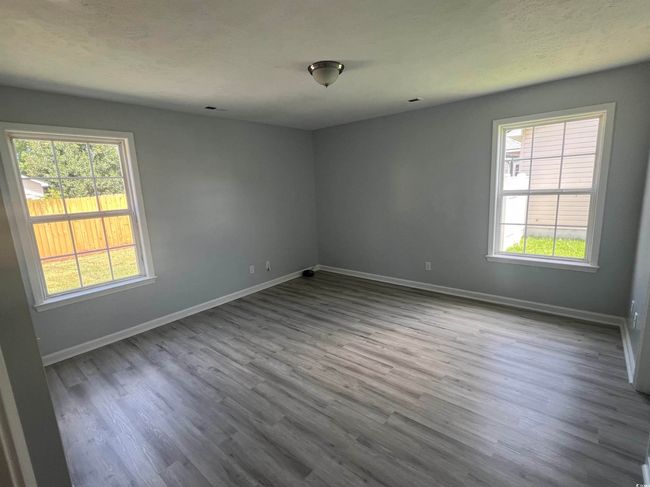 Empty room featuring healthy amount of natural light and dark wood finished floors | Image 5