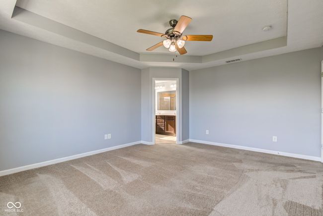 unfurnished room featuring a tray ceiling, ceiling fan, carpet, and a smoke detector | Image 32
